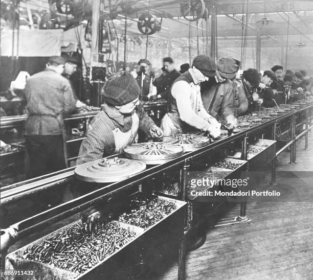 Some workers at the assembly line, making fly wheels for the Ford Model T car in Highland Park Ford Plant. Highland Park, 1914