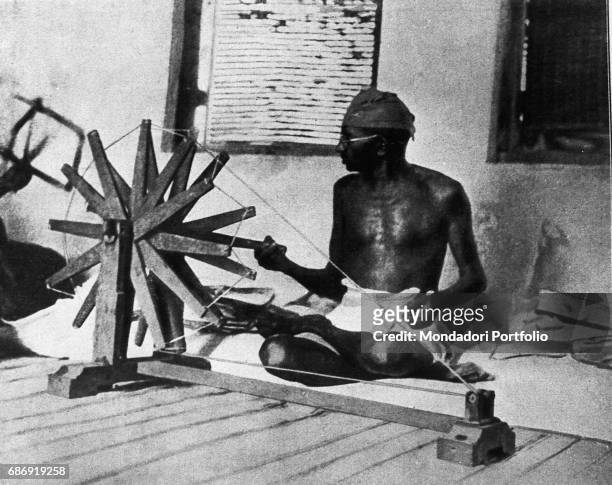 Mahatma Gandhi spinning a cotton-winder. India, 1910s