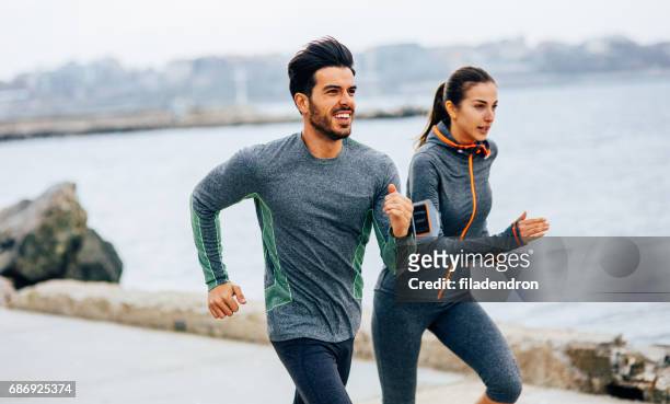 vrienden joggen door de zee - fitness armband stockfoto's en -beelden