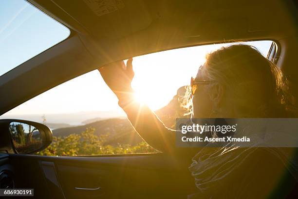 woman looks out car window towards sunrise - car side view mirror stock pictures, royalty-free photos & images