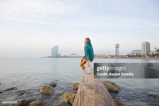 man relaxes on waterfront rail, looks to sea - see far stock pictures, royalty-free photos & images