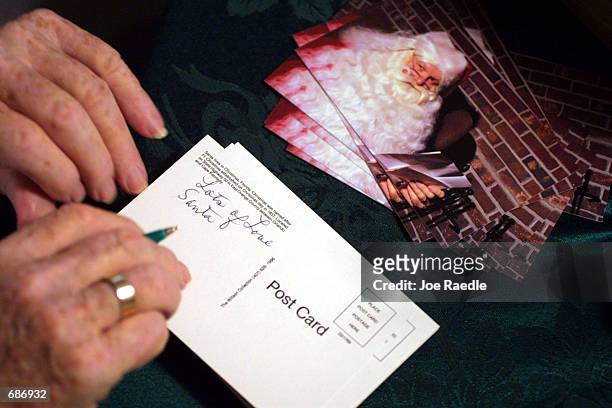 Jack James sits in his living room December 11, 2001 and fills out postcards in response to letters addressed to Santa Claus in Christmas, FL. James...