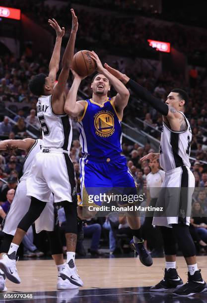 Klay Thompson of the Golden State Warriors drives to the basket against Dejounte Murray and Danny Green of the San Antonio Spurs in the first half...