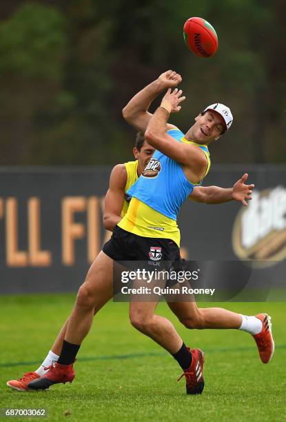 Bailey Rice of the Saints handballs whilst being tackled during a St Kilda Saints AFL training session at Linen House Oval on May 23, 2017 in...