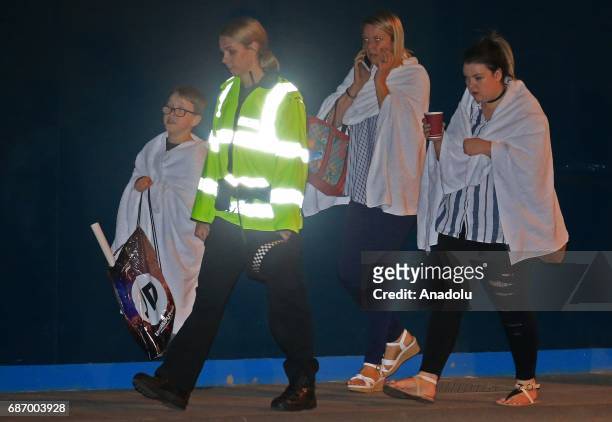 British police officer escorts walking casualties away from the Manchester Arena stadium in Manchester, United Kingdom on May 23, 2017. A large...