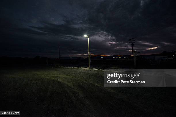 street lamp at edge of dirt parking lot. - street light fotografías e imágenes de stock