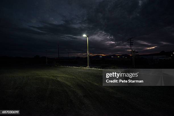 street lamp at edge of dirt parking lot. - street light stock pictures, royalty-free photos & images