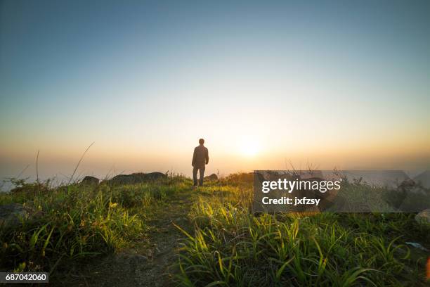 man walking near sunset on top of mountain - man walking silhouette stock pictures, royalty-free photos & images