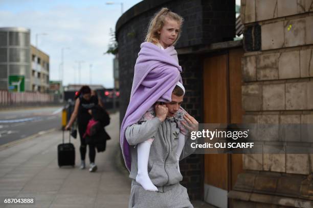Man carries a young girl on his shoulders near Victoria station in Manchester, northwest England on May 23, 2017. Twenty two people have been killed...