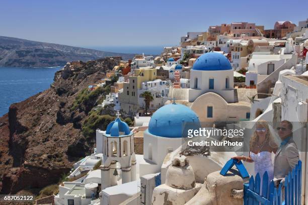 Newly married couple poses for wedding photos while on honeymoon in the village of Oia on Santorini Island, Greece. Santorini Island is without a...