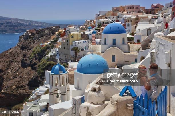 Newly married couple poses for wedding photos while on honeymoon in the village of Oia on Santorini Island, Greece. Santorini Island is without a...