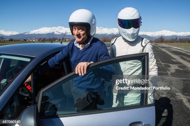 Actor and TV host Claudio Bisio and racing driver The Stig getting into a car in the backstage of the TV show Top Gear Italia. Italy, 1st March 2016