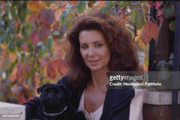 Personality, stylist and socialite italiana Marina Ripa di Meana posing with her dog in her lap. November 1987