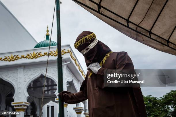 An executor known as 'algojo' stands as prepare public caning for violations against Sharia law at Syuhada mosque on May 23, 2017 in Banda Aceh,...