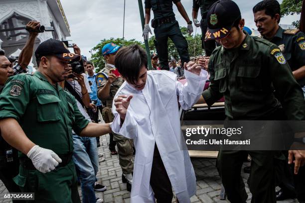 An indonesian man escorted by the sharia police after get caning in public from an executor known as 'algojo' for having gay sex, which is against...