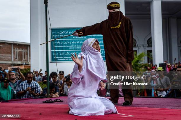 An acehnese woman gets caning in public from an executor known as 'algojo' for spending time with a man who is not her husband, which is against...
