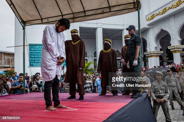 An Indonesian man gets caning in public from an executor known as 'algojo' for having gay sex, which is against Sharia law on May 23, 2017 in Banda...