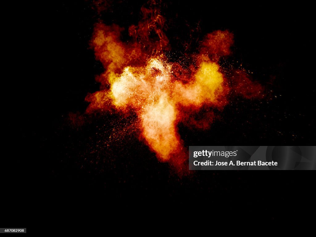 Forms and textures of an explosion of a powder of colors yellow on a black bottom