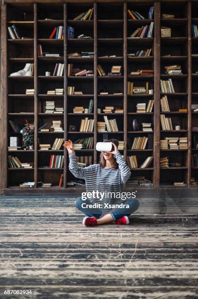 happy woman wearing vr glasses in front of bookshelves - negative photo illusion stock pictures, royalty-free photos & images