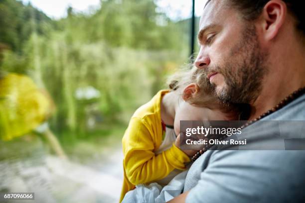 father cuddling with little daughter at the window - lean in collection stock pictures, royalty-free photos & images