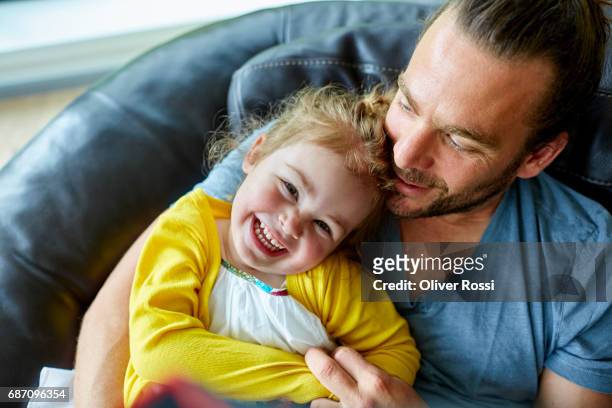 happy father and little daughter on the couch - 2 year old blonde girl father stock pictures, royalty-free photos & images