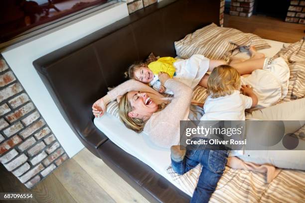 happy mother with two children in bed - auf dem bauch liegen stock-fotos und bilder