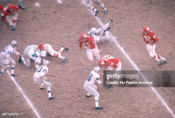 Johnny Robinson of the Dallas Texans runs with the ball as he gets help from teammate Al Reynolds as Jim Crotty and Billy Atkins of the Buffalo Bills...