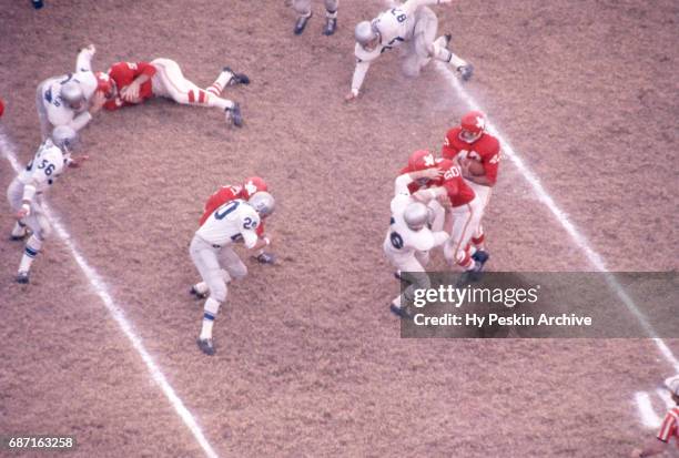 Johnny Robinson of the Dallas Texans runs with the ball as he gets help from teammate Al Reynolds as Jim Crotty and Billy Atkins of the Buffalo Bills...