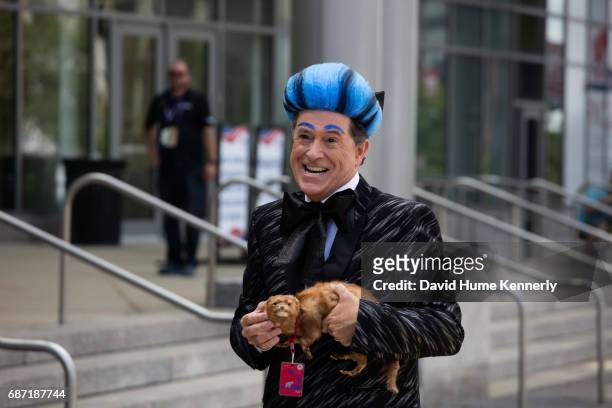 Portrait of American comedian and television host Stephen Colbert, in a costume and with a weasel in his hands, as he stands outside Quicken Loans...