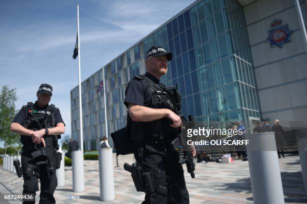 Flags fly at half-mast as armed British Police officers walk on patrol with their weapons outside of Greater Manchester Police force's headquarters...