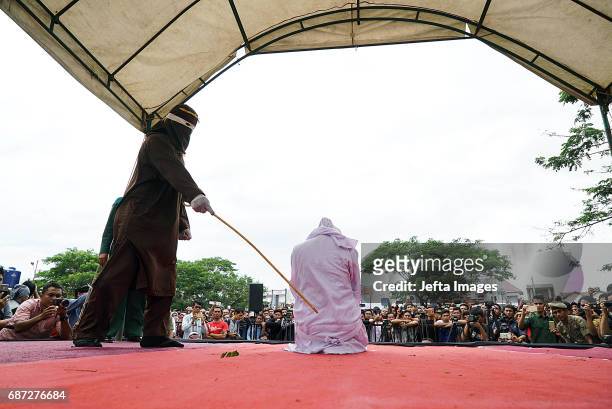 An Acehnese woman is being whipped in public for violating sharia law on May 23, 2017 in Banda Aceh, Indonesia. About four Acehnese couple received...