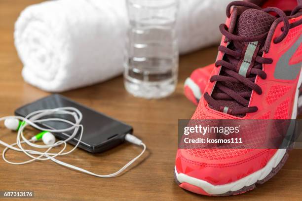 closeup of running shoes and mobile phone headphones on a dark wooden floor