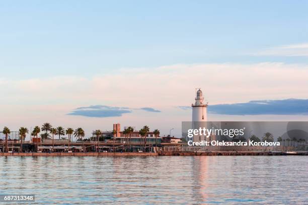 lighthouse on the shoreline of palmeral de las sorpresas port in malaga, andalusia, spain. - costa del sol málaga province stock pictures, royalty-free photos & images