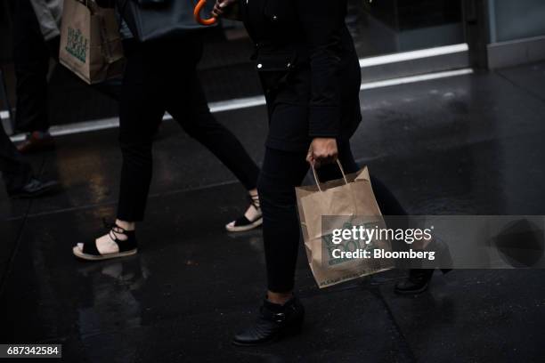 Customer carries a shopping bag outside a Whole Foods Market Inc. Location in New York, U.S., on Tuesday, May 22, 2017. Whole Foods Market Inc.,...