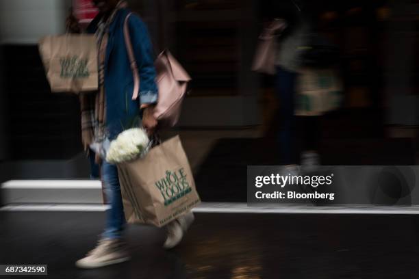 Customer carries shopping bags outside a Whole Foods Market Inc. Location in New York, U.S., on Tuesday, May 22, 2017. Whole Foods Market Inc.,...