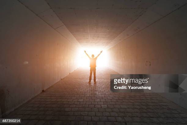 silhouette of a male jumping in a tunnel - luz al final del túnel fotografías e imágenes de stock