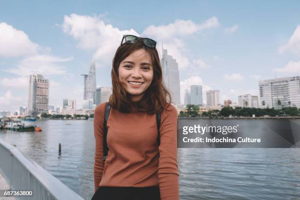 portrait of vietnamese beautiful girl with toothy smile, morden building on background - vietnamesischer abstammung stock-fotos und bilder