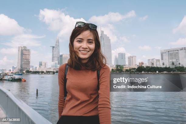 portrait of vietnamese beautiful girl with toothy smile, morden building on background - vietnamese ethnicity stock pictures, royalty-free photos & images