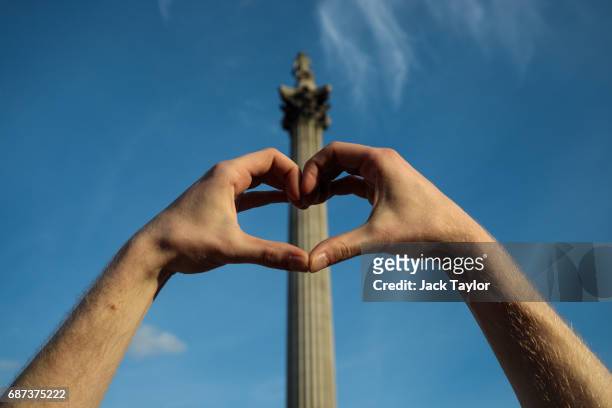 Man creates a heart symbol with his hands in front of Nelson's Column during a vigil for the victims of yesterday's Manchester Arena terror attack in...