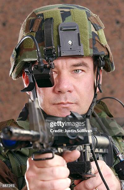 Army Sgt. Chris Augustine points an M4 Carbine Assult rifle as he models the 0.6 Land Warrior System December 13, 2001 at the Homeland Security Expo...