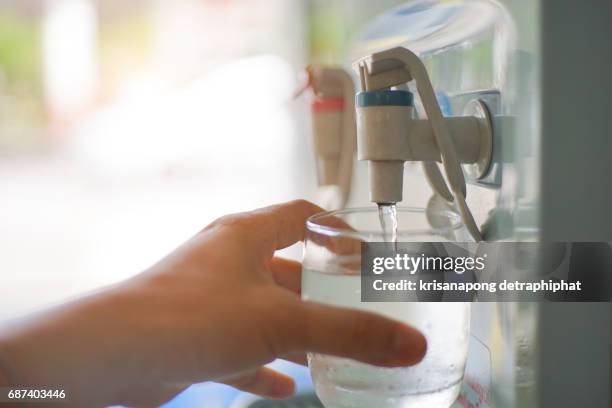 male hand serving water of a water cooler in plastic cup. - water cooler stockfoto's en -beelden