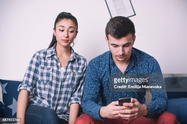 young woman spy on husband's cell phone - suspicion stock pictures, royalty-free photos & images