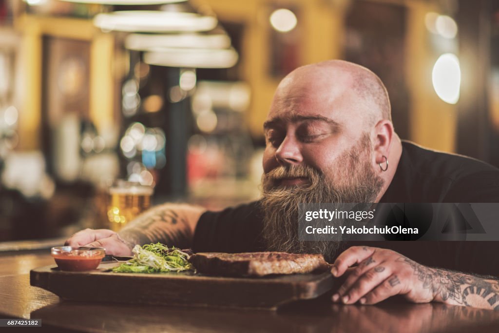 パブで焼肉を味わう肥満の男性