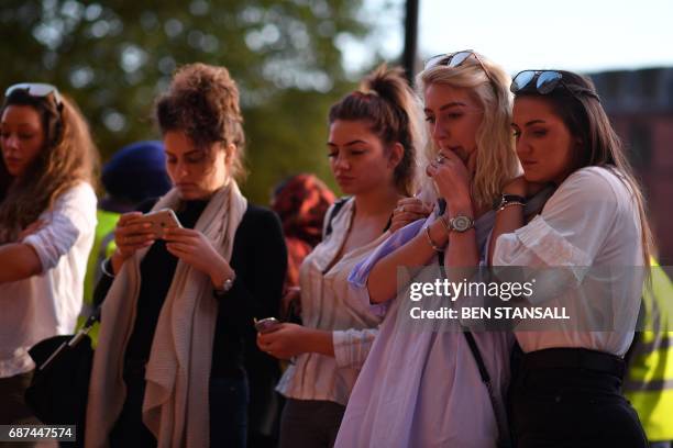 People pause in front of candles set up in front of floral tributes in Albert Square in Manchester, northwest England on May 23 in solidarity with...