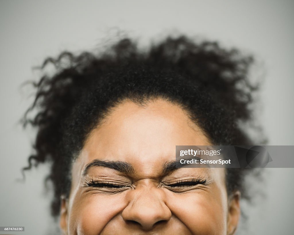 Opgewonden gelukkig Afro Amerikaanse vrouw tegen grijze achtergrond