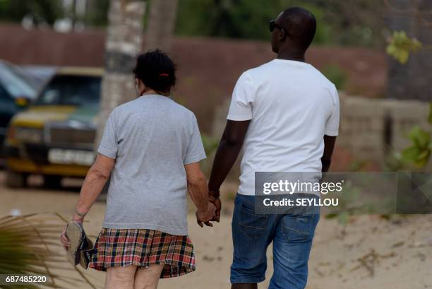 Mixed couple walks on the beach of Kololi on April 9, 2017. For decades, The Gambia has built a reputation as a haven for tourists willing to pay for...