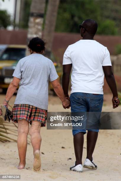 Mixed couple walks on the beach of Kololi on April 9, 2017. For decades, The Gambia has built a reputation as a haven for tourists willing to pay for...