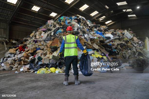 man holding bag of rubbish at rubbish tip - pile of plastic waste stock pictures, royalty-free photos & images