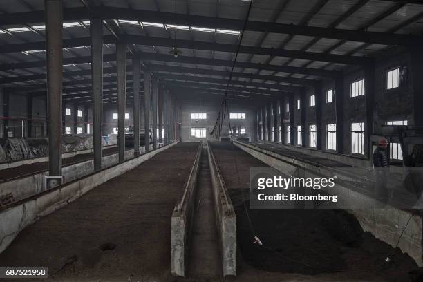 An employee operates a machine to aerate troughs of fermenting animal manure in an organic fertilizer plant at a showcase farm operated by Penglai...