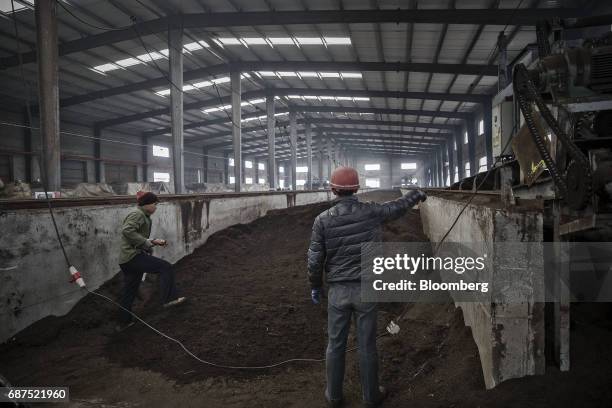 An employee operates a machine to aerate troughs of fermenting animal manure in an organic fertilizer plant at a showcase farm operated by Penglai...
